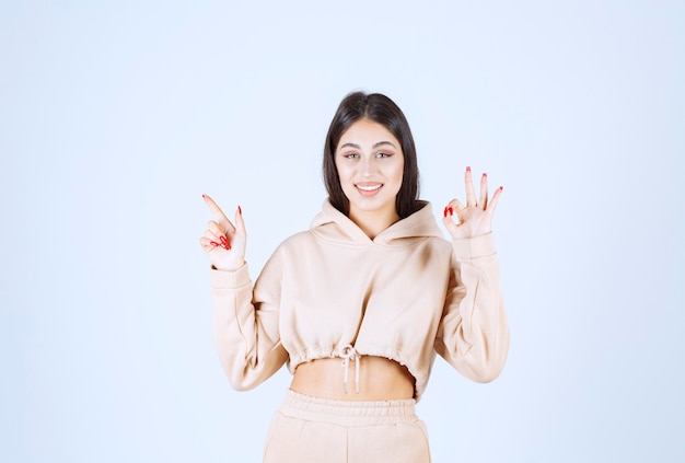 Jeune femme dans un sweat à capuche rose montrant un bon signe de la main