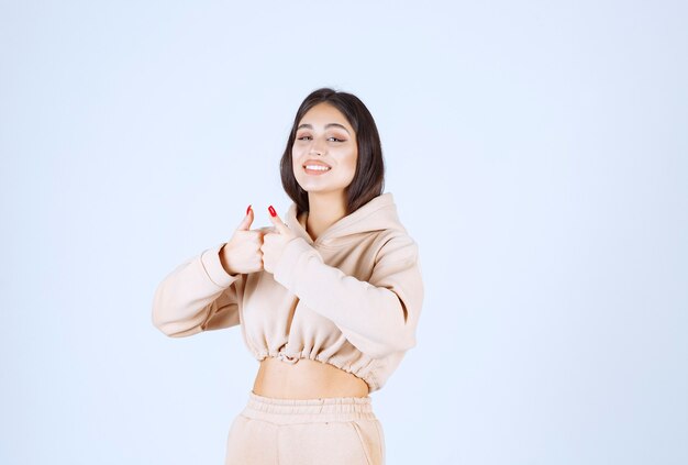 Jeune femme dans un sweat à capuche rose montrant un bon signe de la main