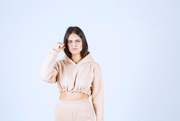 Jeune femme dans un sweat à capuche rose montrant ses muscles