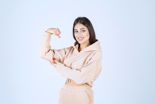 Jeune femme dans un sweat à capuche rose montrant ses muscles