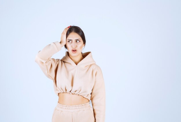 Jeune femme dans un sweat à capuche rose pensant et remue-méninges