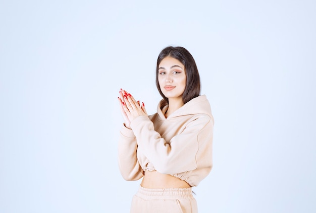 Jeune femme dans un sweat à capuche rose unissant les mains et priant