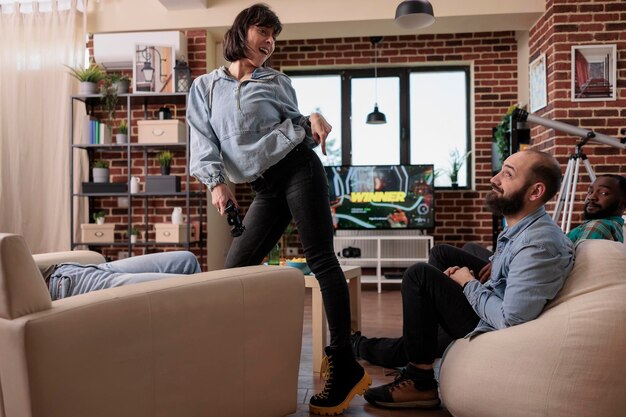 Jeune femme dansant après avoir remporté la stratégie des jeux vidéo, célébré la victoire et joué à la compétition de tir à la télévision. Personne s'amusant avec une grande victoire, appréciant le jeu à la télévision.