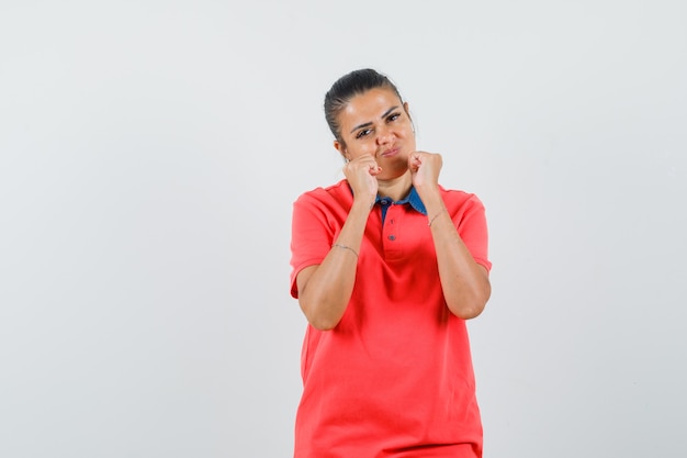 Jeune femme debout en boxeur pose en t-shirt rouge et à la jolie vue de face.