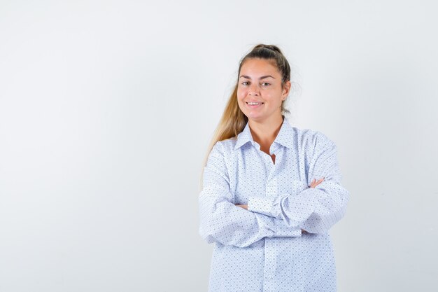 Jeune femme debout les bras croisés en chemise blanche et à la recherche de plaisir