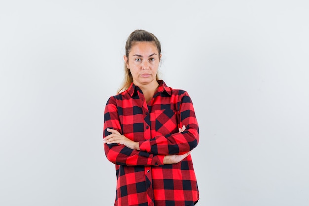 Jeune femme debout avec les bras croisés en chemise à carreaux et à la confiance