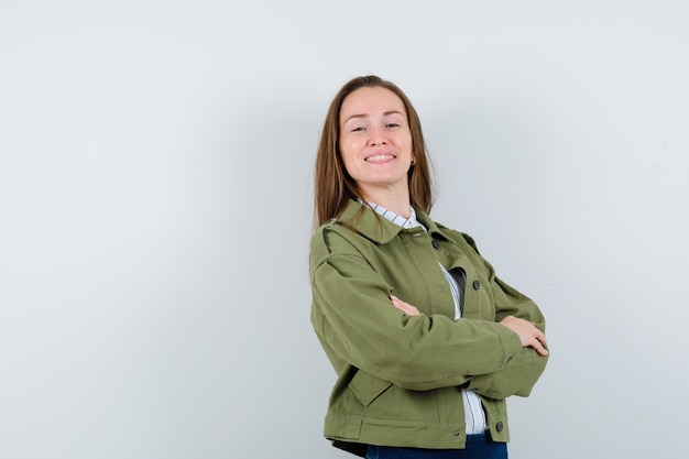 Jeune femme debout avec les bras croisés en chemise, veste et à l'air confiant. vue de face.