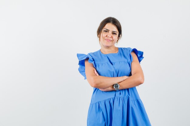 Jeune femme debout avec les bras croisés en robe bleue et à la jovial