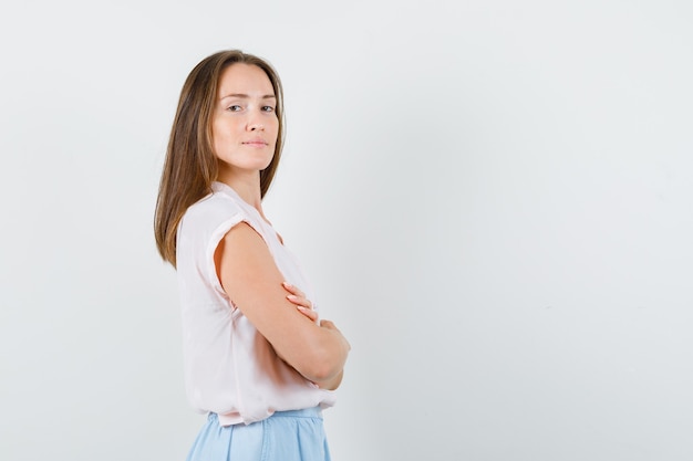 Jeune femme debout avec les bras croisés en t-shirt, jupe et à la confiance. .