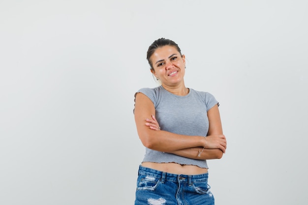 Jeune femme debout avec les bras croisés en t-shirt, short et à la joyeuse.