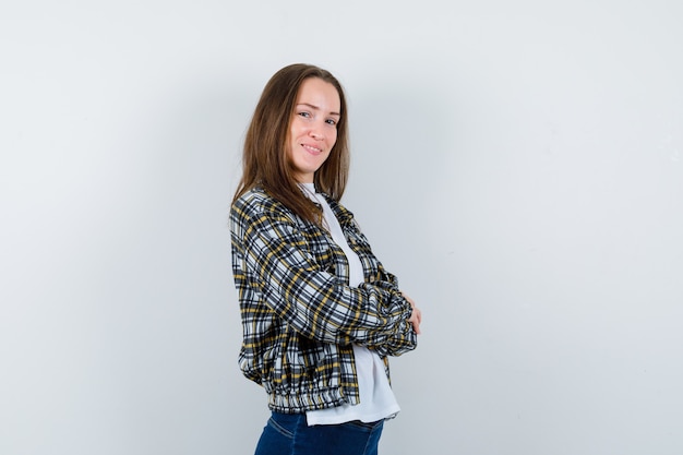 Jeune femme debout avec les bras croisés en t-shirt, veste et à la confiance. vue de face.