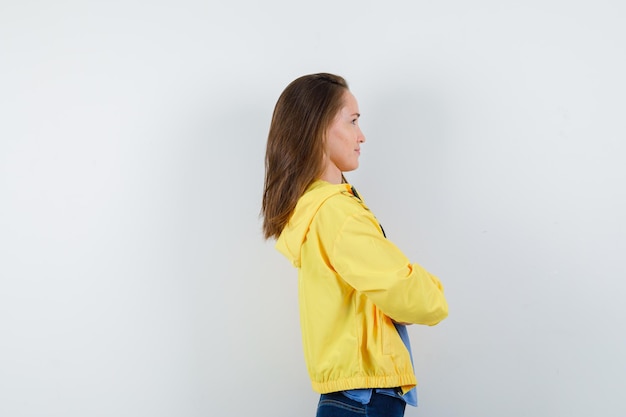 Jeune femme debout avec les bras croisés en t-shirt, veste et à la pensive