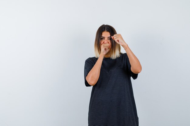 Jeune femme debout dans la lutte contre la pose en robe de polo et à la confiance. vue de face.