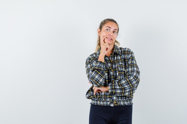 Jeune femme debout dans la pensée pose en chemise, short et à la rêveuse, vue de face.