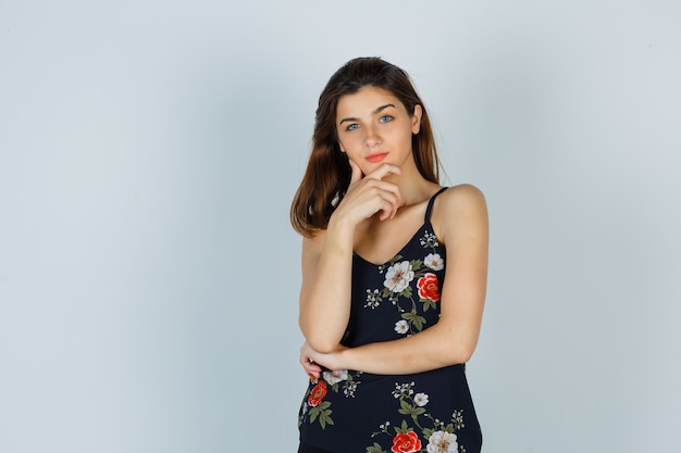 Jeune femme debout dans la pensée pose en haut floral et à la recherche sensible