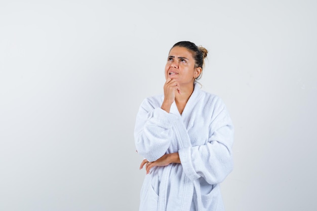 Jeune femme debout dans la pensée pose en peignoir et à la pensive