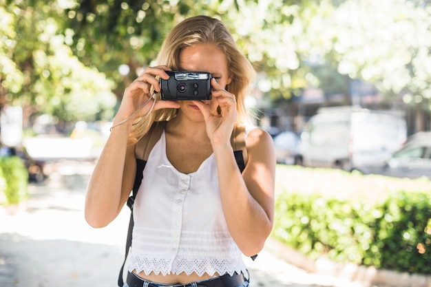 Jeune femme debout à l&#39;extérieur de photographier avec caméra