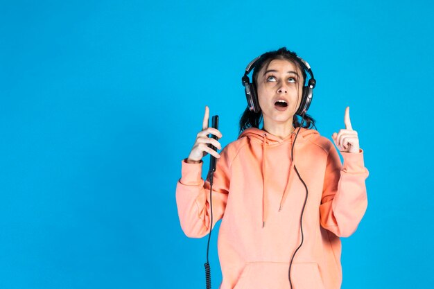 Jeune femme debout sur fond bleu et pointeur vers le haut