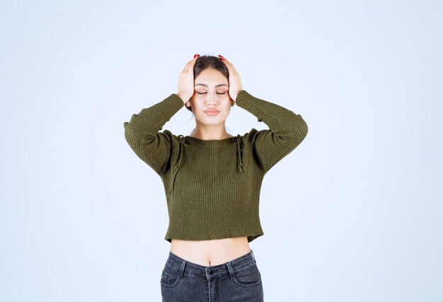 Jeune femme debout avec des maux de tête douloureux sur fond blanc.