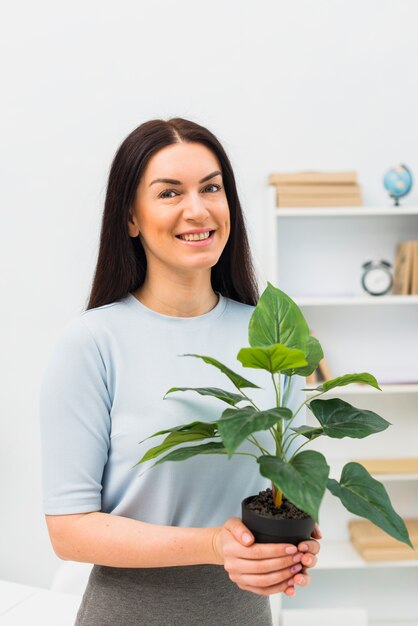 Jeune femme, debout, à, plante verte, dans, pot fleur