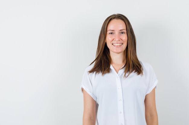 Jeune femme debout en riant en chemisier blanc et à la joyeuse.