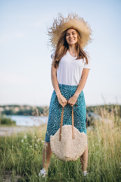 Jeune femme, debout, à, sac, à, grand chapeau, dans, champ