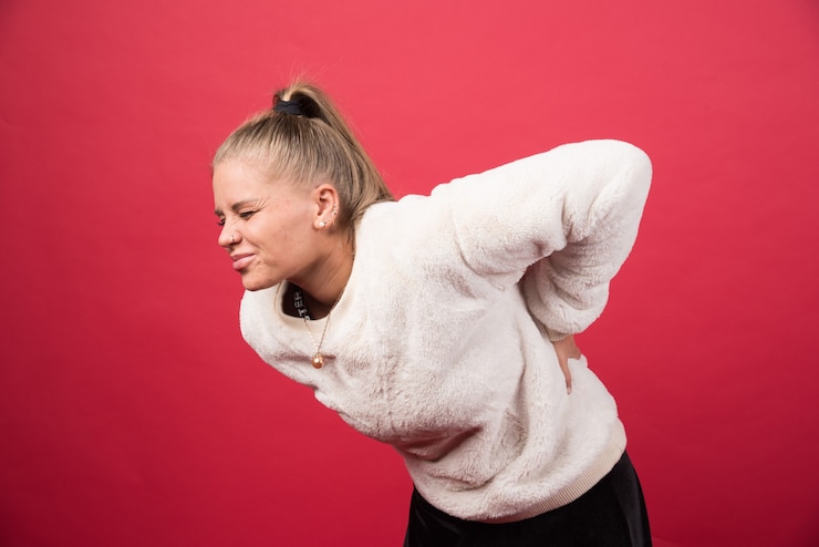 Photo gratuit une jeune femme debout et touchant le bas du dos ressentant des sensations douloureuses photo de haute qualité