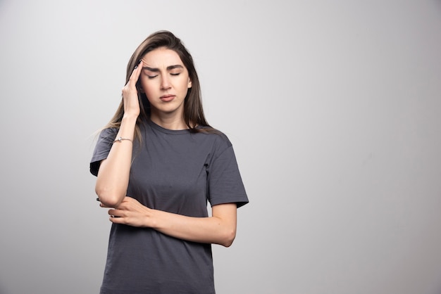 Jeune femme debout et touche sa tête de douleur