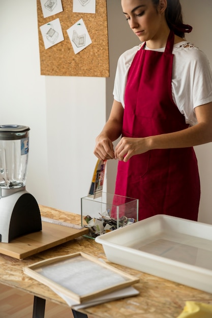 Photo gratuite jeune femme déchire le papier sur le récipient en verre