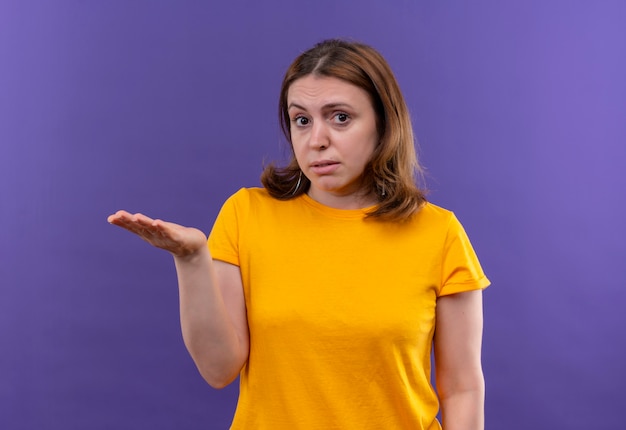 Jeune femme décontractée montrant une main vide sur un mur violet isolé