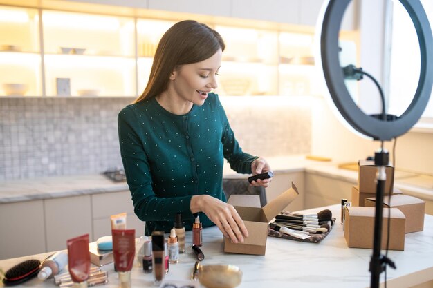 Jeune femme démontrant de nouveaux produits cosmétiques et semblant impliquée