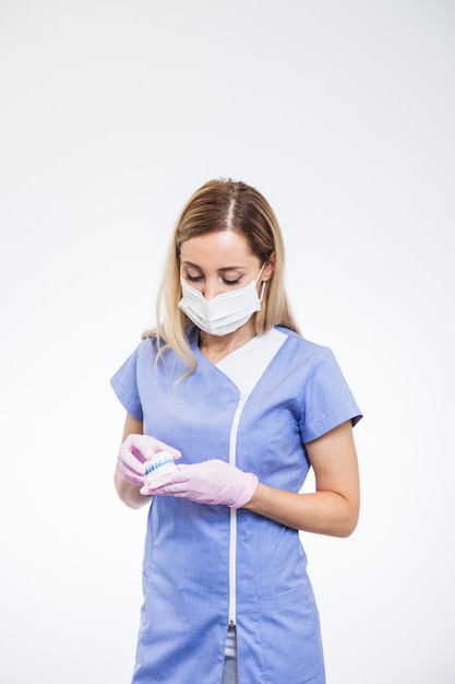 Jeune femme dentiste tenant le modèle de dents sur fond blanc