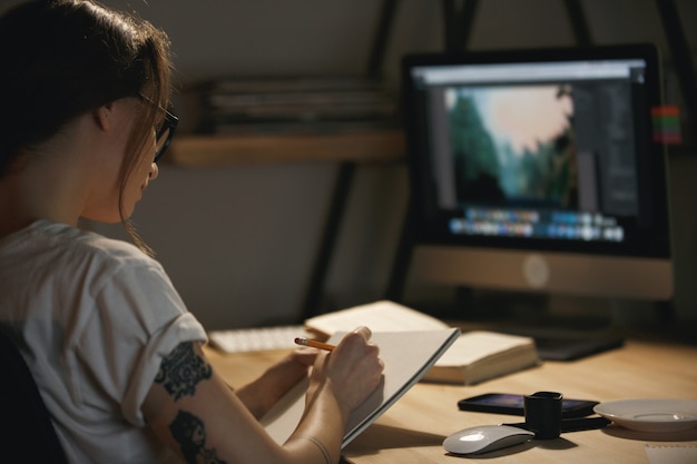 Jeune femme designer assis à l'intérieur la nuit croquis dessin