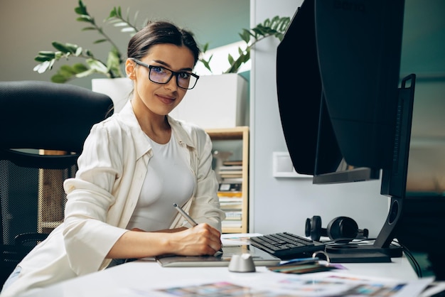 Jeune femme designer numérique travaillant sur tablette et ordinateur