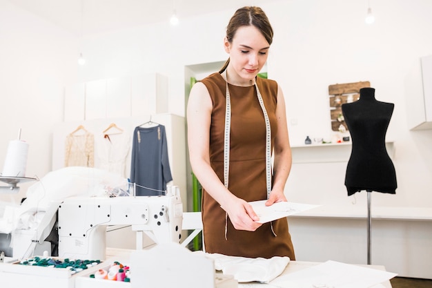 Jeune femme designer tenant des croquis de mode dans le magasin