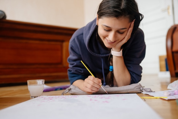 Photo gratuite jeune femme dessin allongé sur le sol à la maison