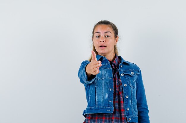 Jeune femme donnant la main pour trembler en chemise, veste et à la gracieuse. vue de face.