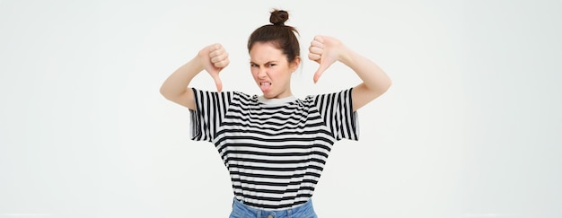 Photo gratuite la jeune femme donne des commentaires négatifs montre le pouce vers le bas désapprouve le produit n'aime pas smth mauvais stands