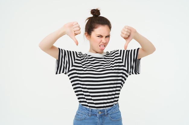 Photo gratuite la jeune femme donne des commentaires négatifs montre le pouce vers le bas désapprouve le produit n'aime pas smth mauvais stands