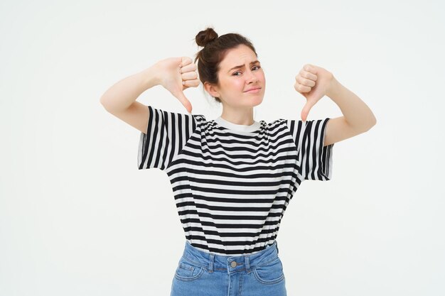 La jeune femme donne des commentaires négatifs montre le pouce vers le bas désapprouve le produit n'aime pas smth mauvais stands