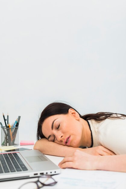 Jeune femme dormant à table avec ordinateur portable