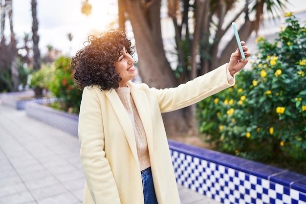 Jeune femme du Moyen-Orient exécutive souriante confiante faire selfie par smartphone au parc