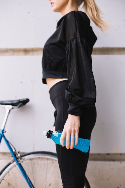 Photo gratuite jeune femme avec de l'eau près de vélo