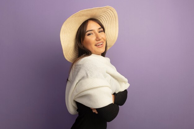 Jeune femme avec écharpe blanche et chapeau d'été souriant joyeusement