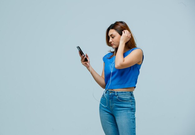 Jeune femme écoutant de la musique avec des écouteurs sur téléphone mobile