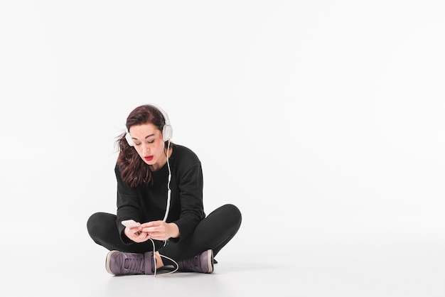 Photo gratuite jeune femme écoutant de la musique à travers un casque sur un lecteur mp3