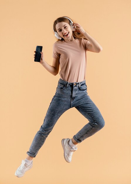 Jeune femme avec des écouteurs et saut mobile