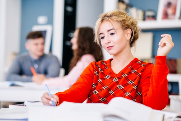 Jeune femme écrivant dans le manuel de la bibliothèque