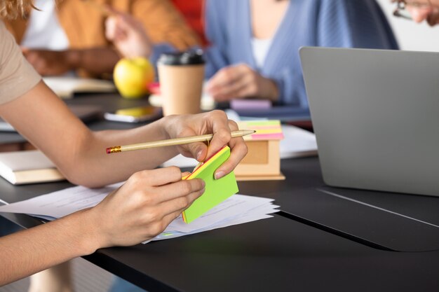 Jeune femme écrivant des informations sur des notes autocollantes pendant la session d'étude