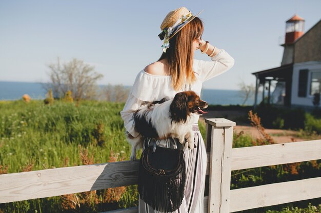 Jeune femme élégante à la campagne, tenant un chien